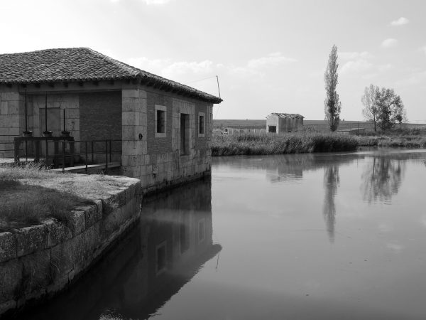 Fotografía artística en blanco y negro de casa de piedra junto al agua