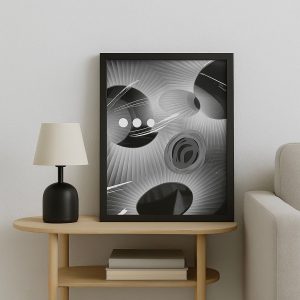 Lámina vertical en blanco y negro con formas abstractas circulares, líneas gráficas y texturas en espiral. Enmarcada en negro, tamaño real 35x40 cm, apoyada sobre mesa de madera clara junto a una lámpara negra.