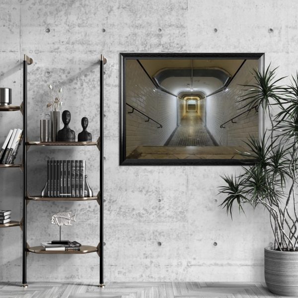 Lámina fotográfica de un túnel con azulejos blancos enmarcada en negro, colgada en la pared de un bar con decoración industrial y sillas altas junto a una barra de madera.
