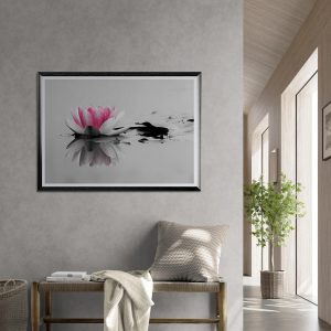 Fotografía artística de una flor de loto rosa sobre agua en blanco y negro, enmarcada y colgada en una pared de estilo minimalista y elegante.